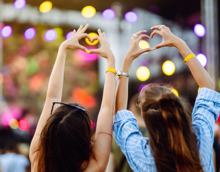 two concert-goers make heart gestures with their hands at bottlerock in napa